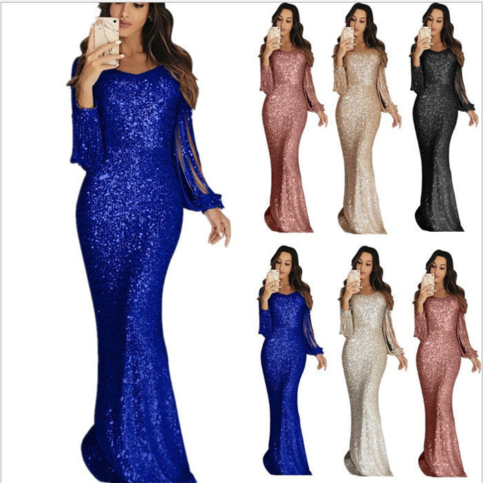 A woman wearing a long sleeve tassel dinner dress in silver color.