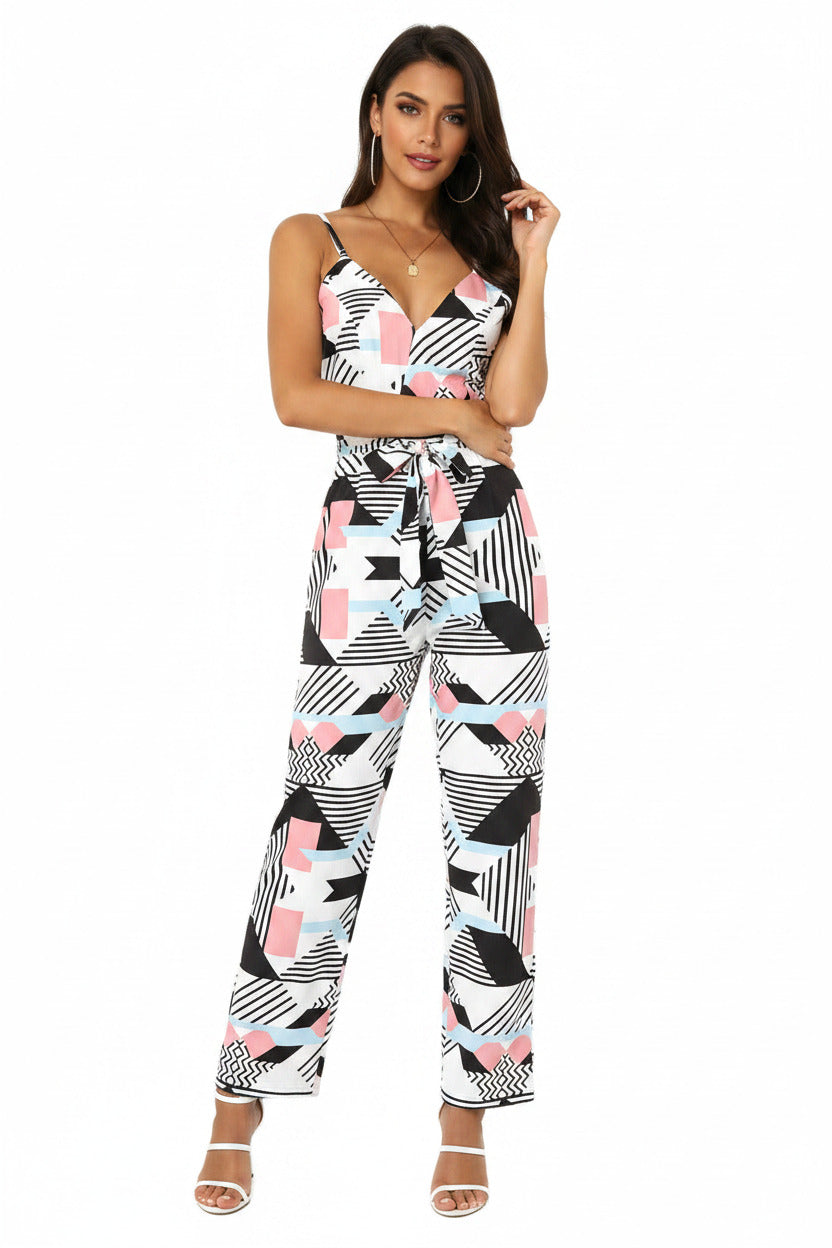 A woman wearing a floral printed jumpsuit with long legs, spaghetti straps, and a belt.