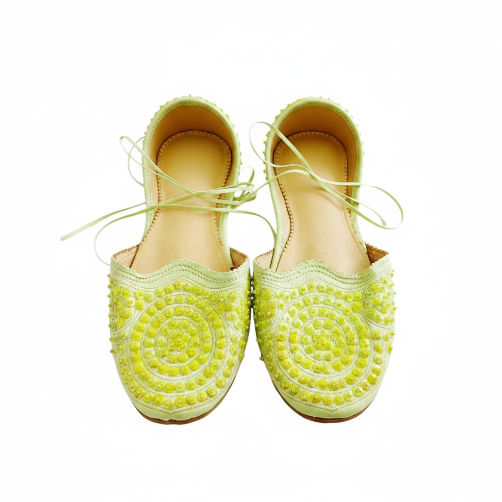 Pair of lime green shoes with decorative patterns on a white background