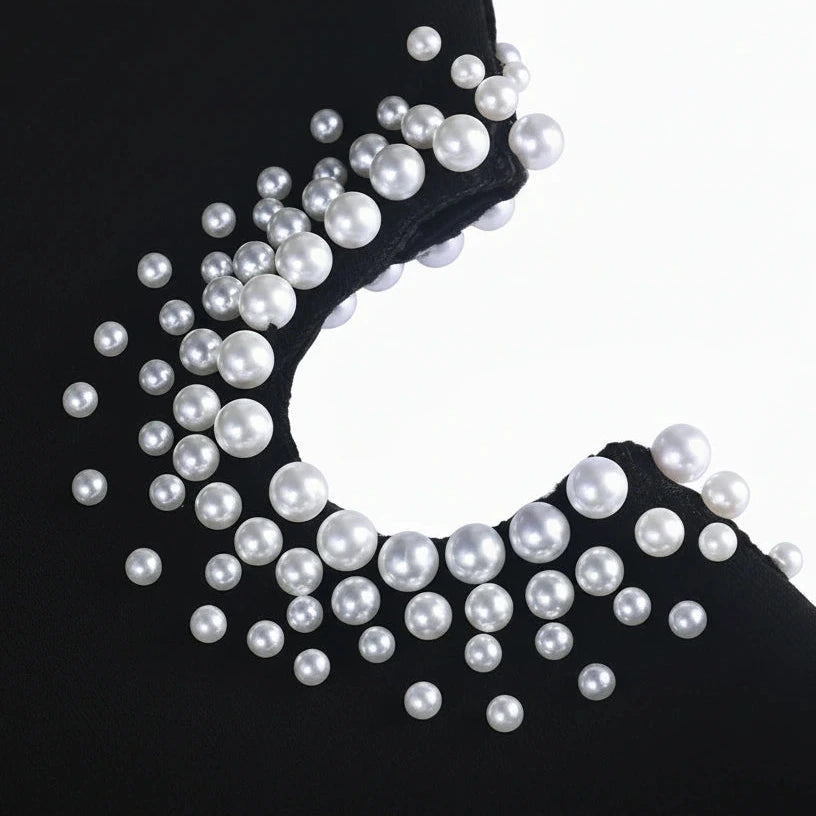 Black fabric with scattered white pearls on a white background