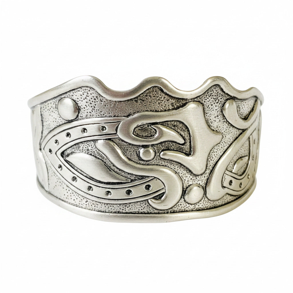 A vintage silver cuff bracelet with intricate carvings, displayed against a white background.