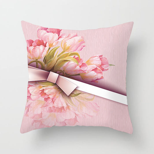 Decorative pillow with pink floral design and bow on a light gray background