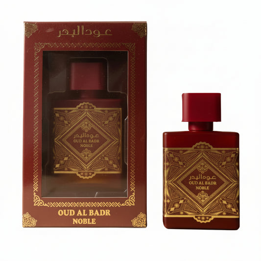Oud Al Badar Noble cologne featuring a dark red rectangular bottle with gold ornate detailing and a matching dark red box with a clear window, displayed against a white background. 