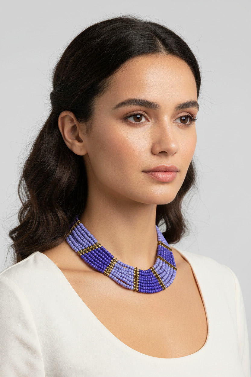 A multi-strand beaded necklace with a gradient of purple and light blue beads, accented by gold spacer rings and a gold clasp, shown on a plain white background.