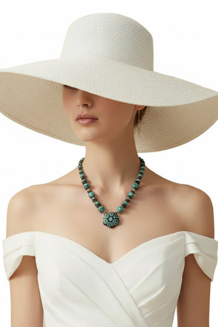 A beaded necklace featuring a large hexagonal pendant with turquoise and brown spiral patterns, flanked by dark brown and turquoise beads with metallic spacer details, shown against a plain white background.
