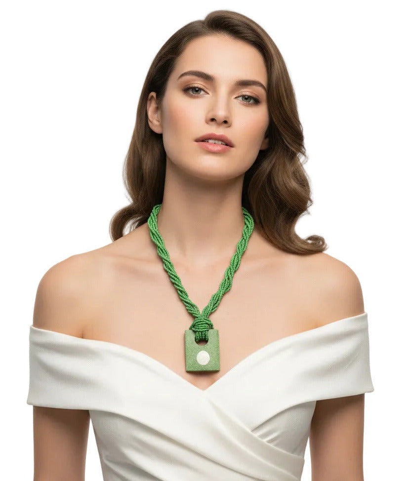 A green beaded necklace with a knotted cord and a rectangular green pendant featuring a white spiral shell in the center, shown on a plain white background.