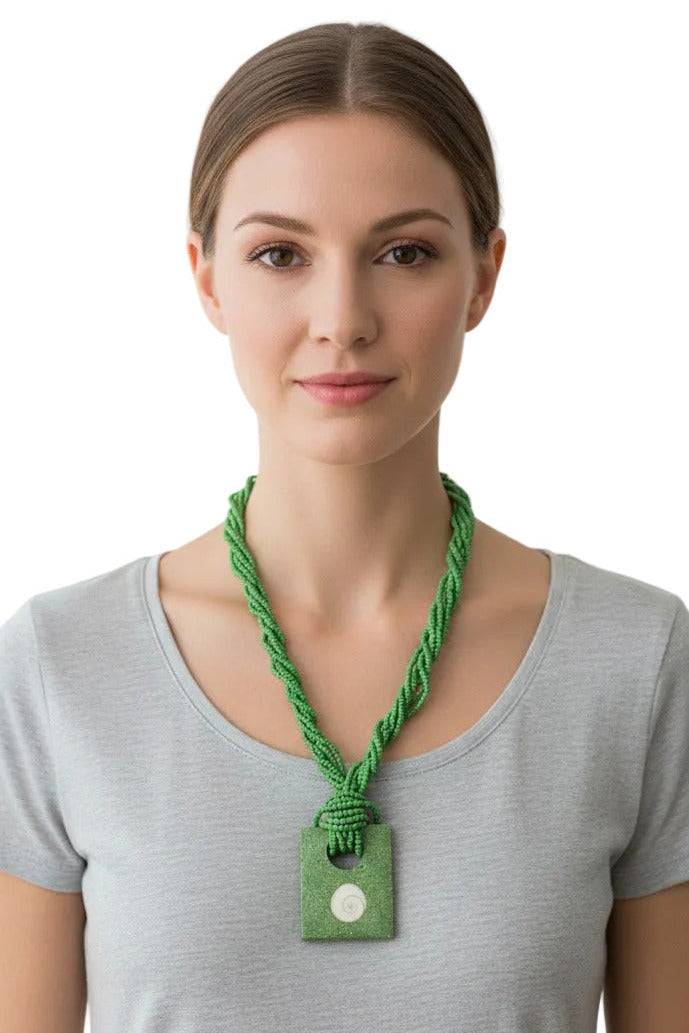 A green beaded necklace with a knotted cord and a rectangular green pendant featuring a white spiral shell in the center, shown on a plain white background.