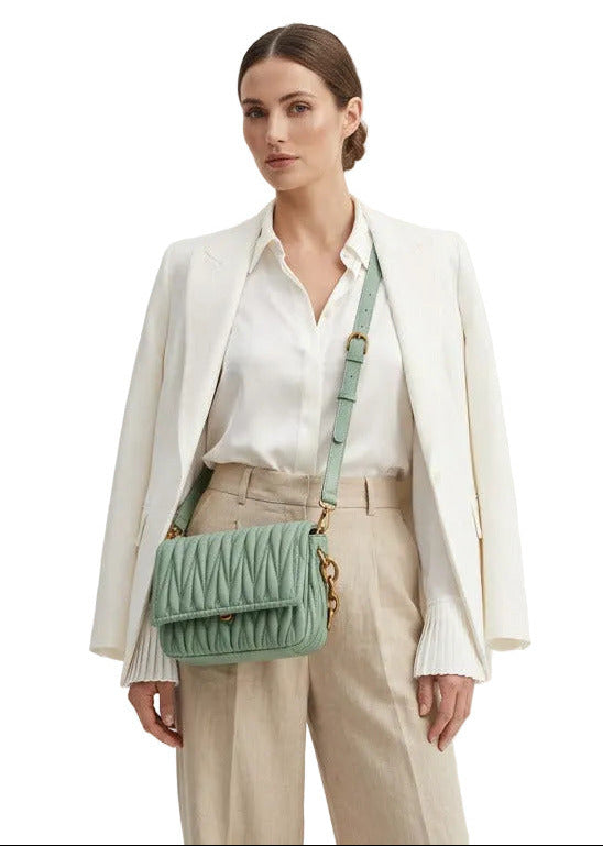 woman carrying a sage green shoulder bag on white background.