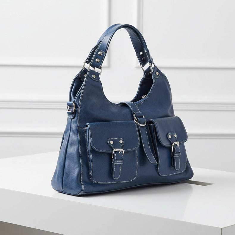 Blue leather handbag with silver buckles on a light gray background