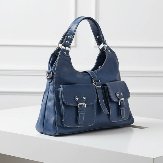 Blue leather handbag with silver buckles on a light gray background