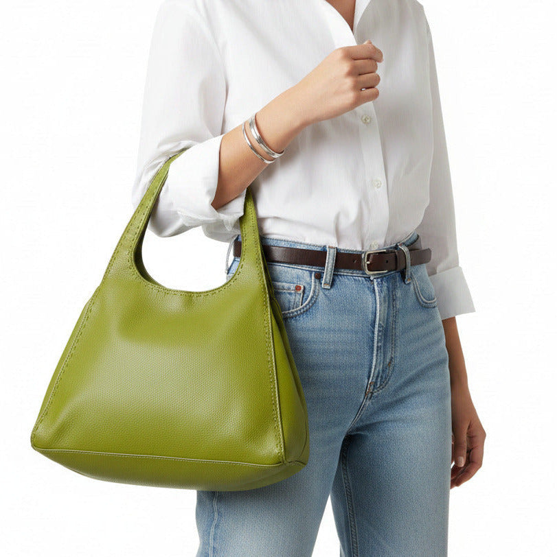 A woman holding a green leather handbag on a light gray background