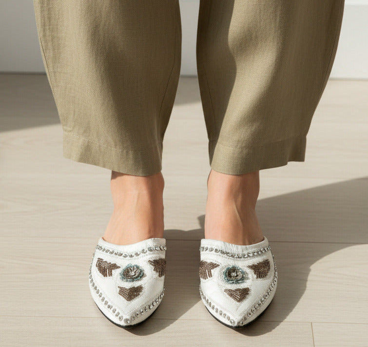 Pair of embellished shoes with floral designs on a white background