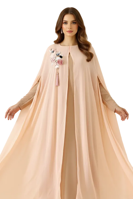 Woman wearing a long, flowing peach dress with floral embroidery against a neutral background