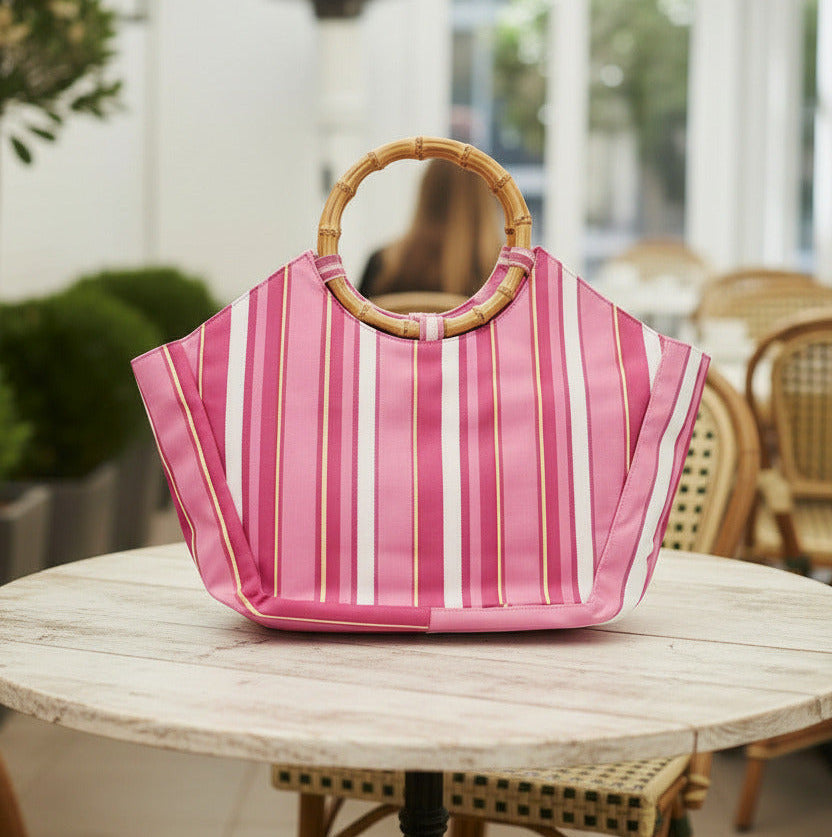 Pink and white striped bag with a bamboo handle on a light pink background