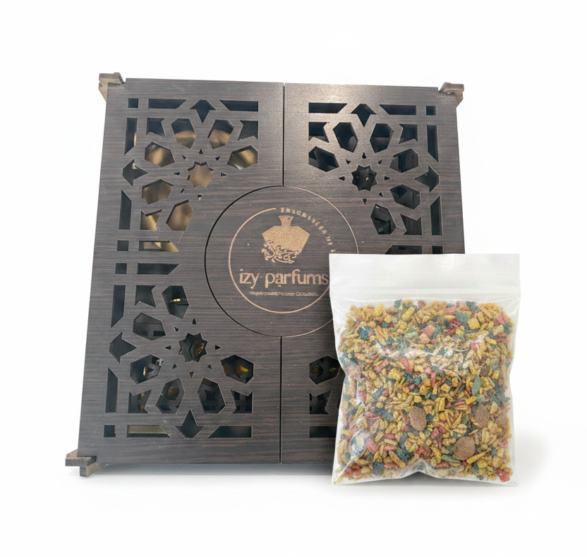 A dark brown wooden box with intricate geometric cutouts and a circular logo reading 'izy parfums', shown alongside a clear plastic bag filled with colorful dried incense herbs on a white background.
