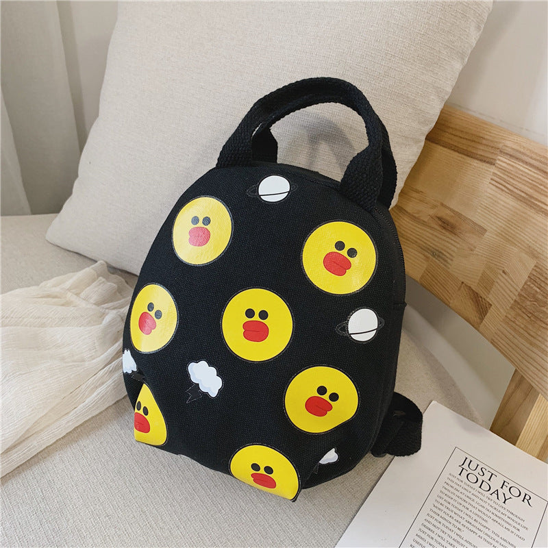A black small round bag with emojis on a surface with a pillow and wooden chair in the background.