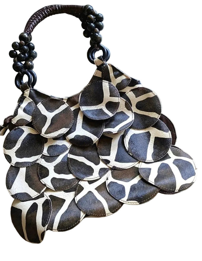 A woman carrying a brown and cream patterned handbag with decorative handle on a white background