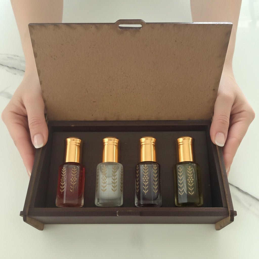 A dark brown wooden presentation box with its door open, containing four small Musk oil bottles with gold caps and geometric patterns.