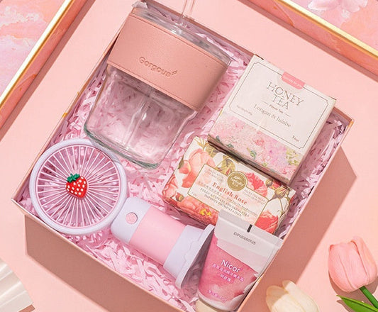 Pink souvenir set with various items including a perfume bottle, fan, and boxes on a pink background.